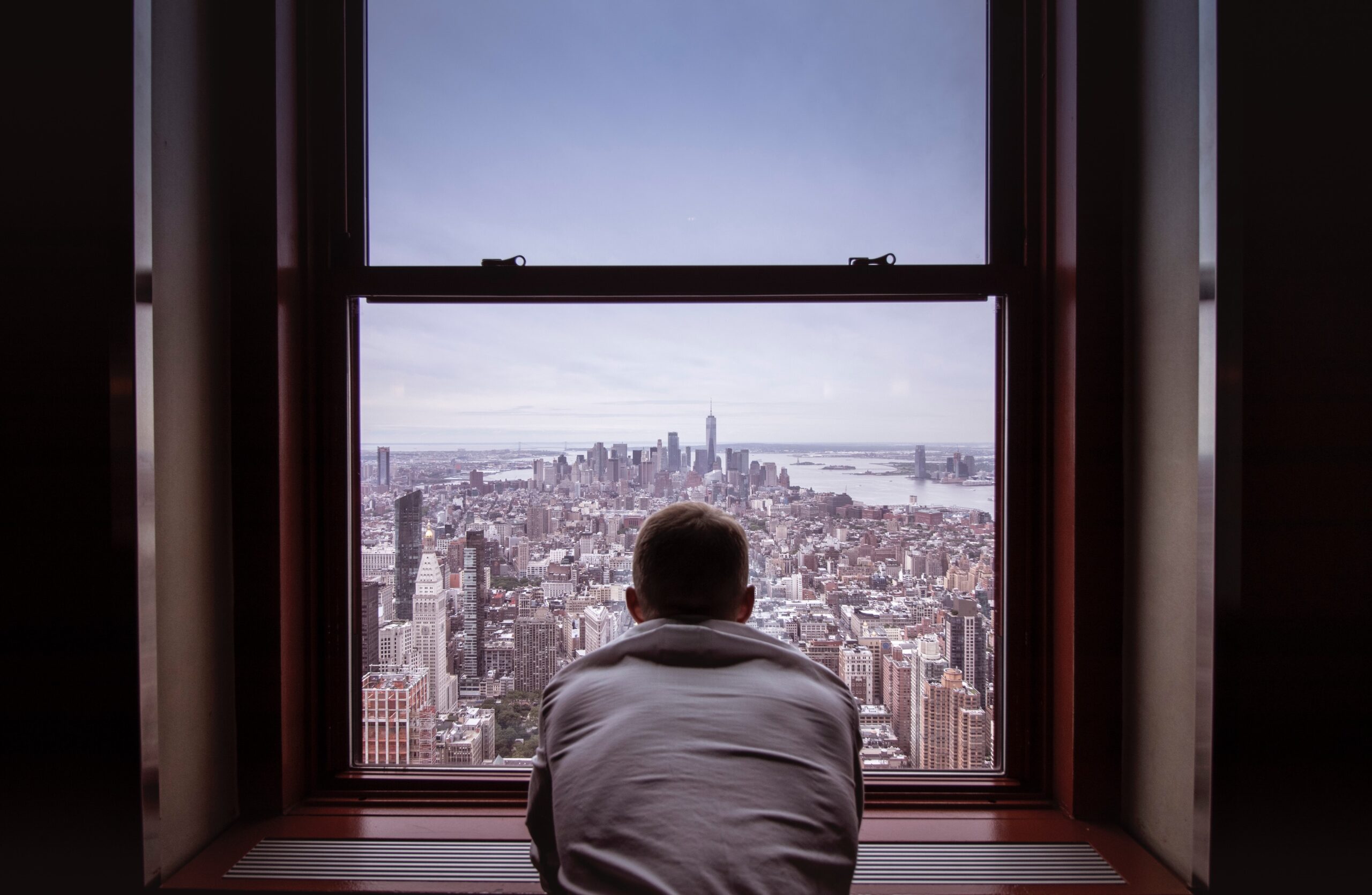man looking out a window over new york